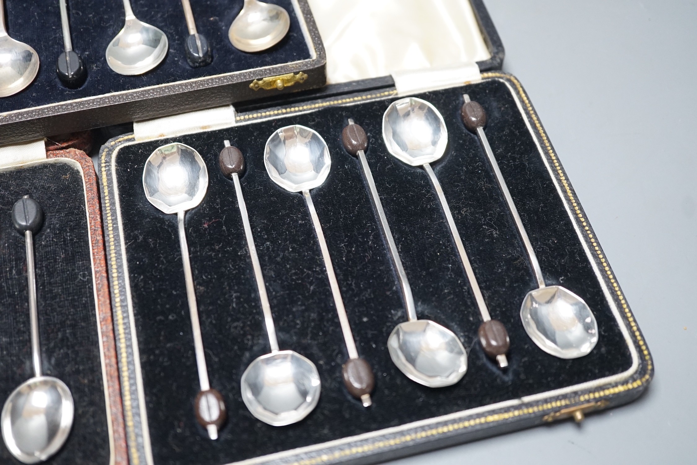 Three assorted cased sets of six silver bean end coffee spoons.